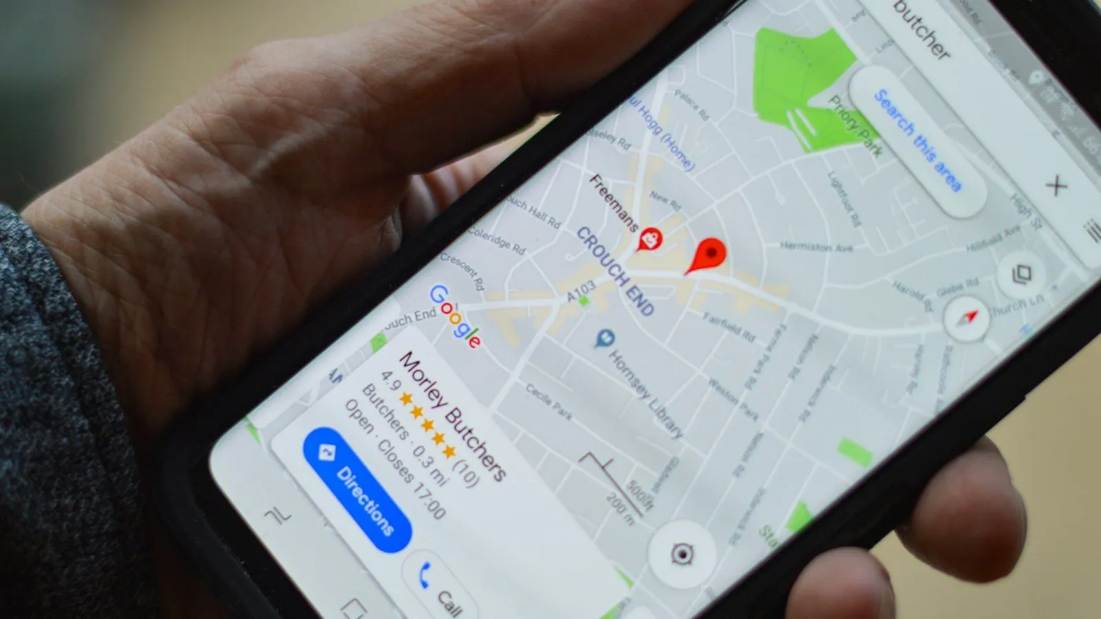 Hand holding a smartphone showing a business location on Google Maps